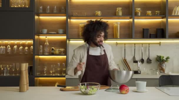 Egyptische chef danst sprenkelende salade met kruiden in keuken — Stockvideo