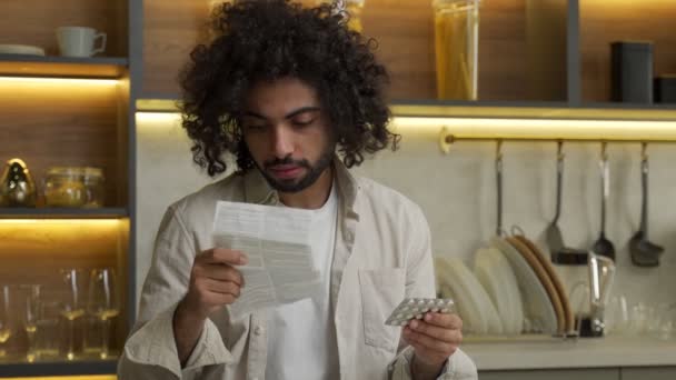 Egipcio hombre lee píldoras manual de instrucciones en la cocina — Vídeo de stock