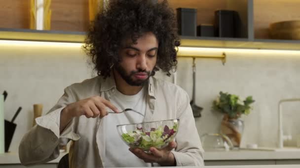 Egipcjanin lubi jeść sałatkę przy stole w nowoczesnej kuchni — Wideo stockowe