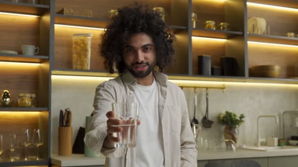 Homem muçulmano estende mão segurando vidro de água na cozinha — Vídeo de Stock