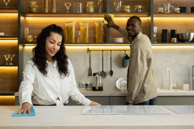 Genç çift modern mutfağı süngerle temizliyor.