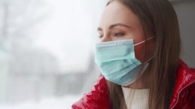 Kadın otobüs penceresinden şehrin kış manzarasına bakıyor.