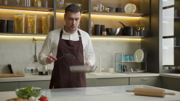 Junger Koch wirft in Küche gedünstetes Gemüse auf Pfanne — Stockvideo