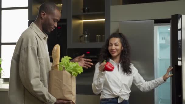 Jovem casal coloca produtos na geladeira comprados na mercearia — Vídeo de Stock