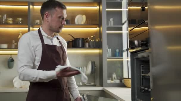 Jovem chef tira biscoitos cozidos do forno na cozinha — Vídeo de Stock