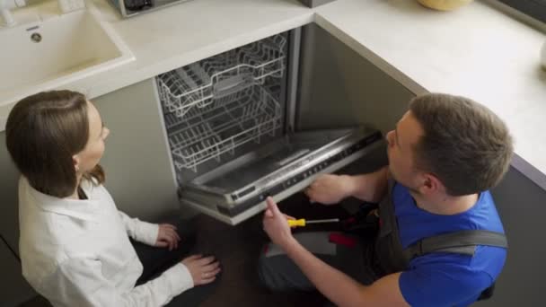 Professional specialist shows fixed dishwasher to woman — Stock Video