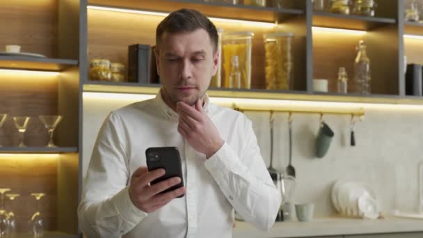 Homem assiste vídeos em redes sociais via smartphone em casa — Vídeo de Stock