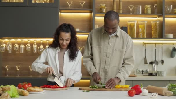 Jovem casal fala cortando legumes frescos para salada — Vídeo de Stock