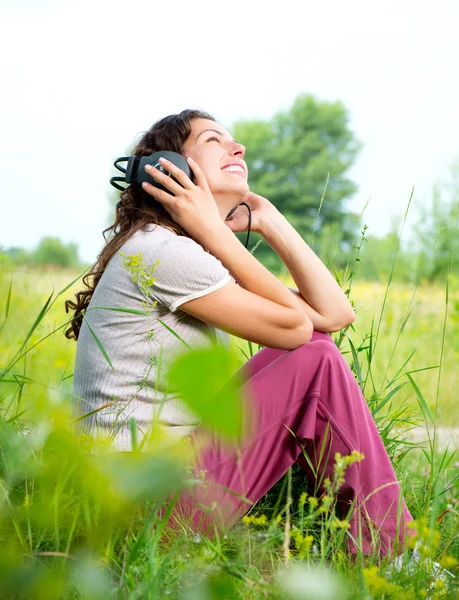 Gyönyörű fiatal nő, fejhallgató szabadban. Élvezze a zenét — Stock Fotó