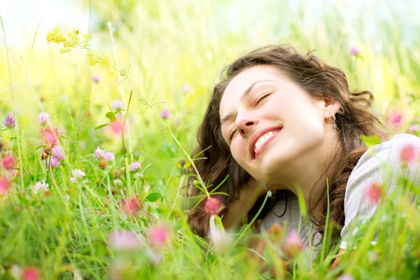 Όμορφη νεαρή γυναίκα ξαπλωμένη στο Λιβάδι των λουλουδιών. Απολαύστε την φύση — Φωτογραφία Αρχείου