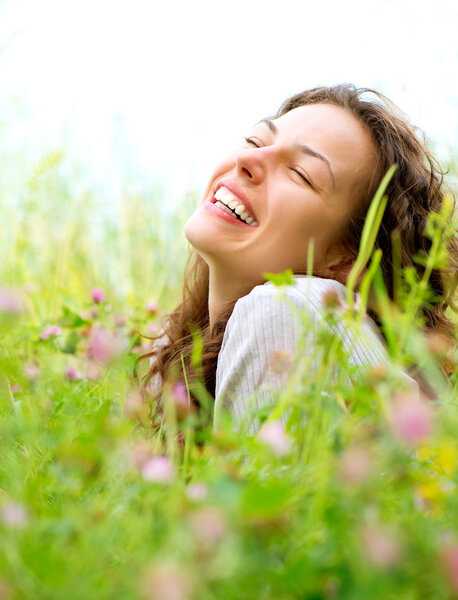 Beautiful Young Woman lying in Meadow of Flowers. Enjoy Nature