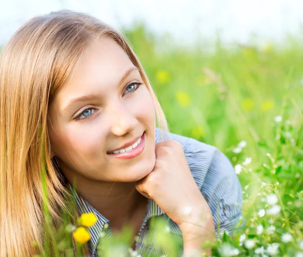 Mooi meisje liggend op weide van bloemen en groen gras — Stockfoto