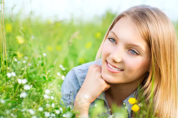 Vacker flicka liggande på äng med blommor och grönt gräs — Stockfoto