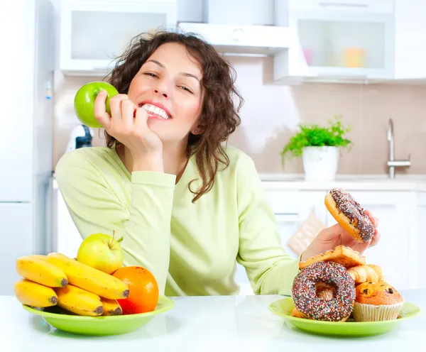 Diet. vacker ung kvinna att välja mellan frukt och godis — Stockfoto