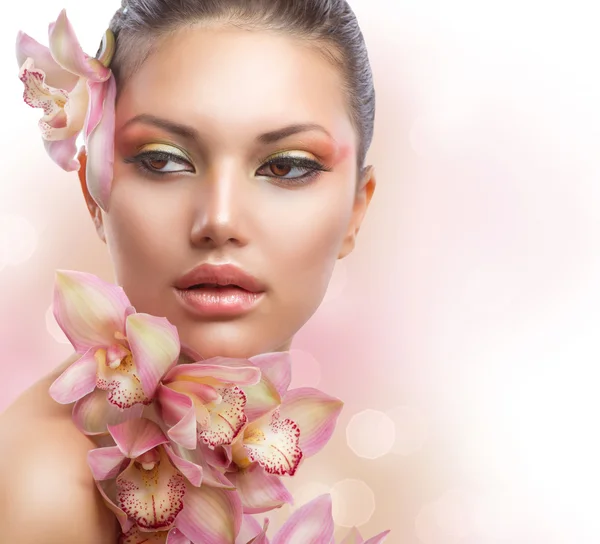 Hermosa chica con flores de orquídea. Maquillaje perfecto —  Fotos de Stock