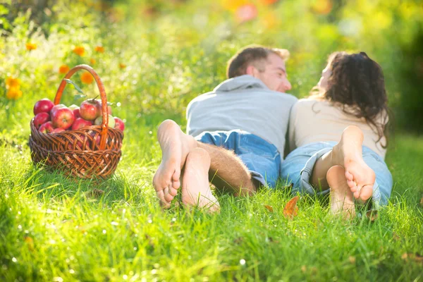 Пара отдыхает на траве и ест яблоки в осеннем саду — стоковое фото