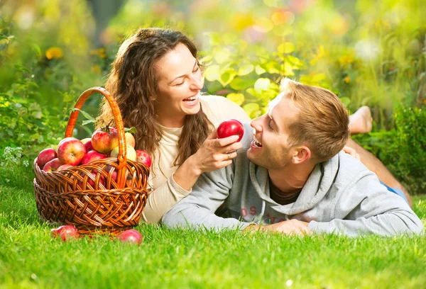 Pár relaxování v trávě a jíst jablka v podzimní zahradě — Stock fotografie