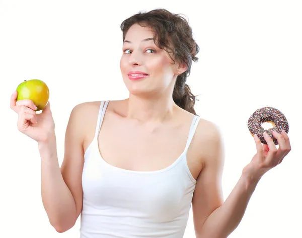Диета. Красивая молодая женщина выбирает между фруктами и пончиками — стоковое фото