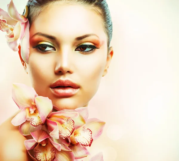 Hermosa chica con flores de orquídea. Belleza mujer cara —  Fotos de Stock