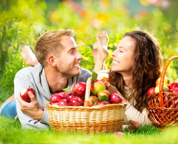 Pareja Relajarse en la hierba y comer manzanas en el jardín de otoño — Foto de Stock