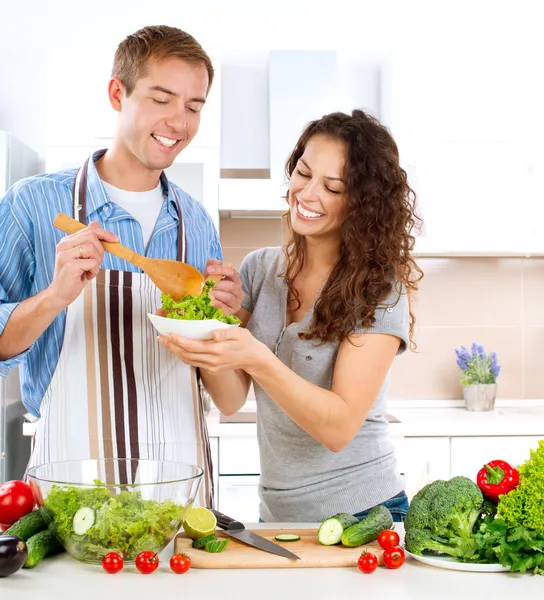 Junger Mann kocht. glückliches Paar isst frischen Gemüsesalat — Stockfoto