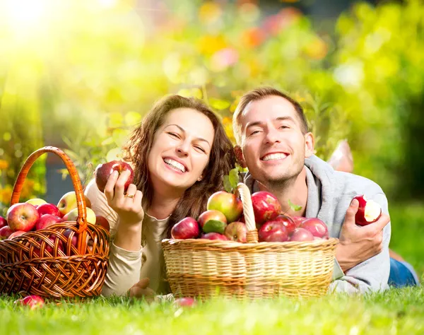 Paar entspannt auf dem Gras und isst Äpfel im herbstlichen Garten — Stockfoto