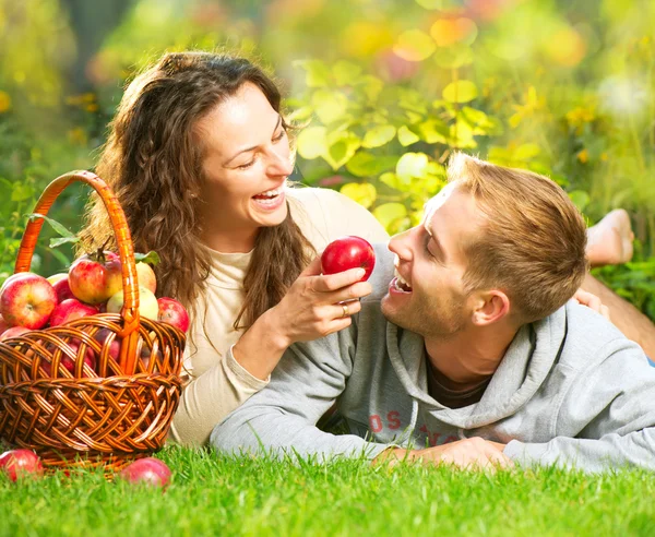 Couple Relaxing on the Grass and Eating Apples in Autumn Garden Stock Picture