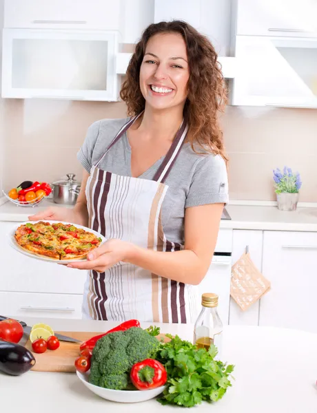 Šťastná mladá žena vaří pizzu doma — Stock fotografie