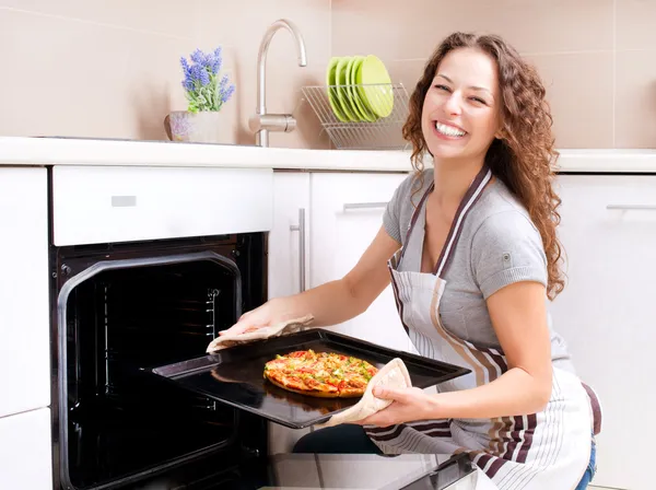 Счастливая молодая женщина готовит пиццу дома — стоковое фото