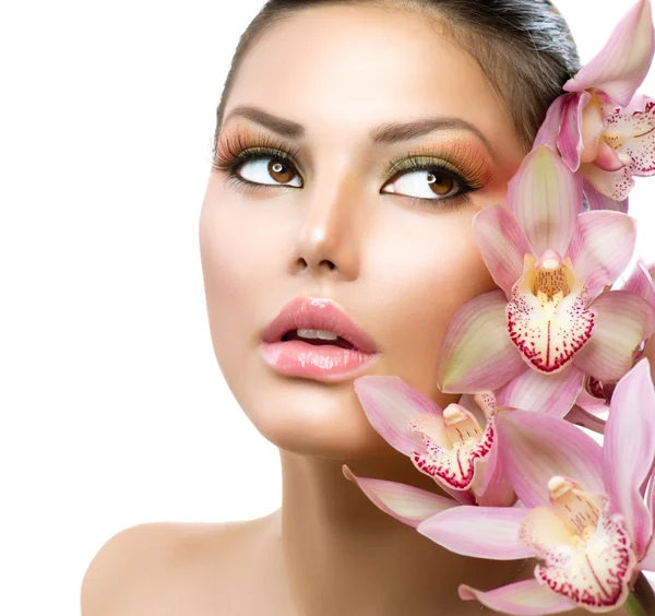 Piękna dziewczyna z kwiaty orchidei. twarz uroda wzór kobiety — Zdjęcie stockowe