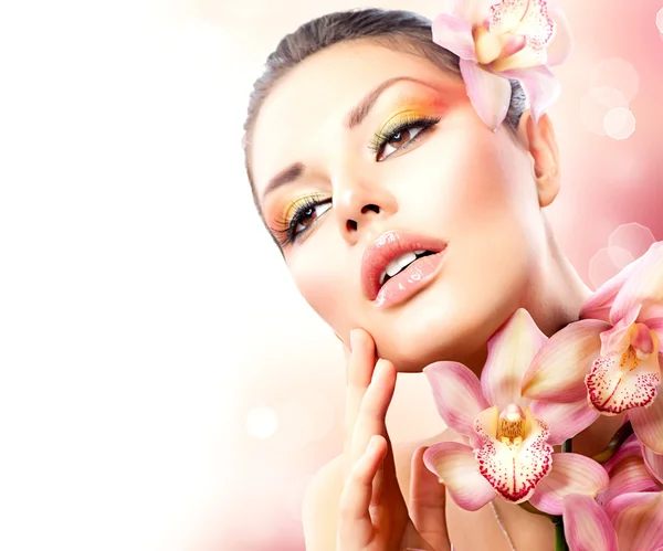 Bella ragazza della stazione termale con i fiori del Orchid che toccano la sua faccia — Foto Stock