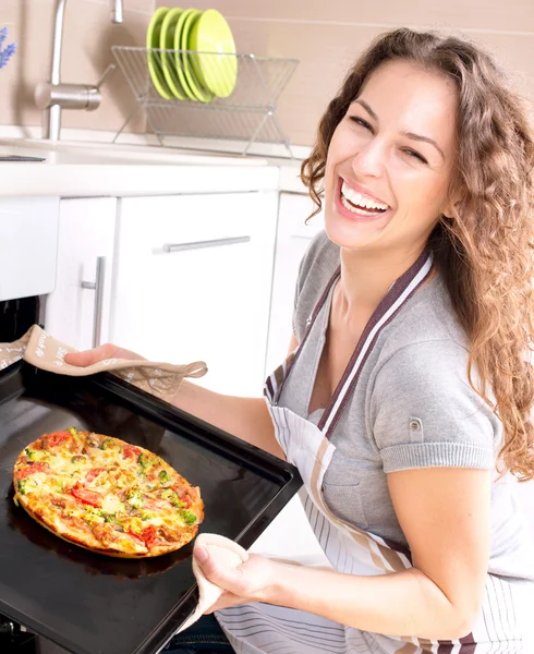 Glad ung kvinna matlagning pizza hemma — Stockfoto