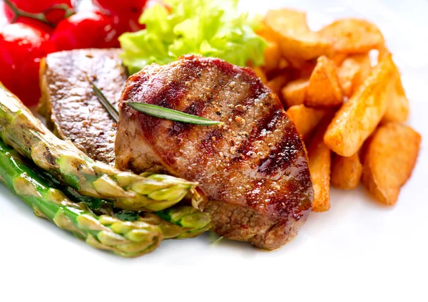 Carne de bife grelhada com batata frita, espargos, tomates — Fotografia de Stock