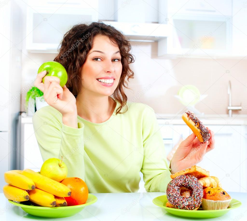 Dieting concept. Young Woman choosing between Fruits and Sweets