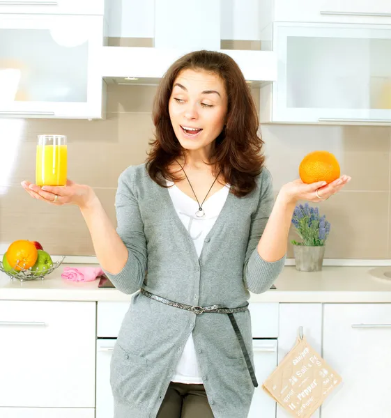 Mulher engraçada escolhendo entre suco de laranja ou laranja inteira — Fotografia de Stock