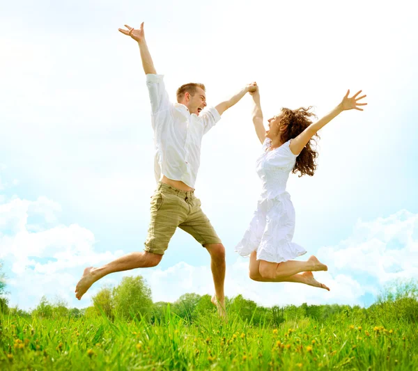 Happy Couple Outdoor. Jumping Family on Green Field — Stock Photo, Image