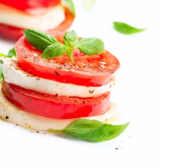 Caprese Salad. Rajčata a mozzarella plátky s listy bazalky — Stock fotografie