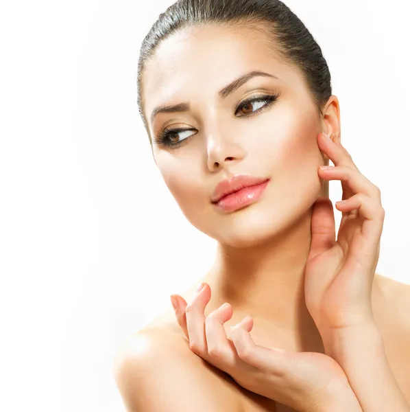 Güzel genç bir kadın yüzüne dokunuyor.