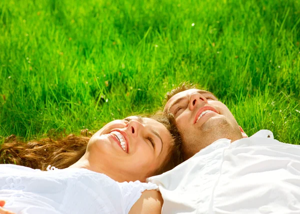 Pareja sonriente feliz Relajándose en la hierba verde. Parque — Foto de Stock