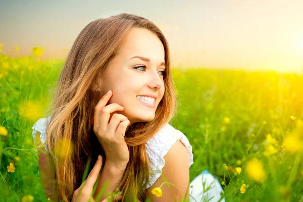 Schoonheid meisje in de weide liggend op groen gras met wilde bloemen — Stockfoto