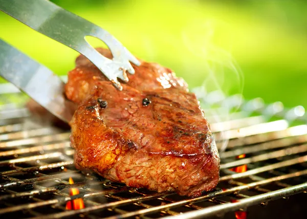 Fiamme che grigliano una bistecca al barbecue. Grill Beef Steak Barbeque Immagini Stock Royalty Free