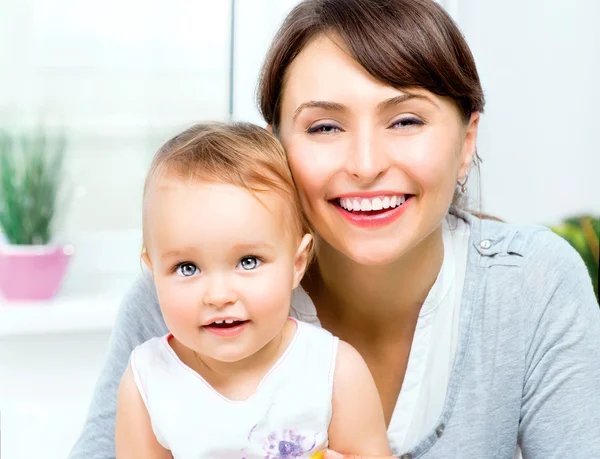 Gelukkig lachend moeder en baby zoenen en knuffelen thuis — Stockfoto