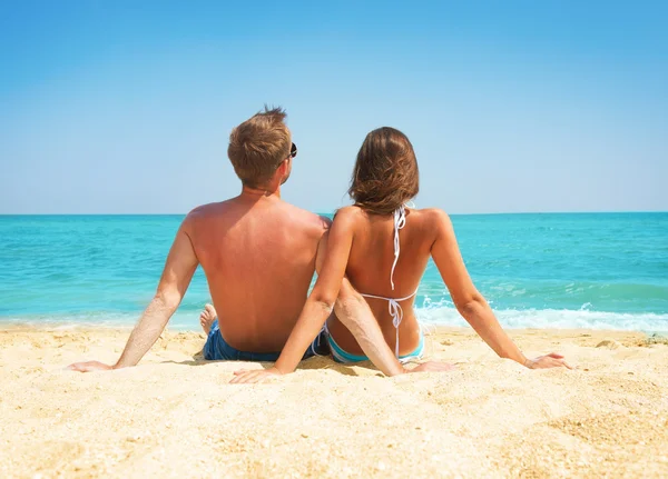 Pareja joven sentados juntos en la playa. Concepto de vacaciones — Foto de Stock