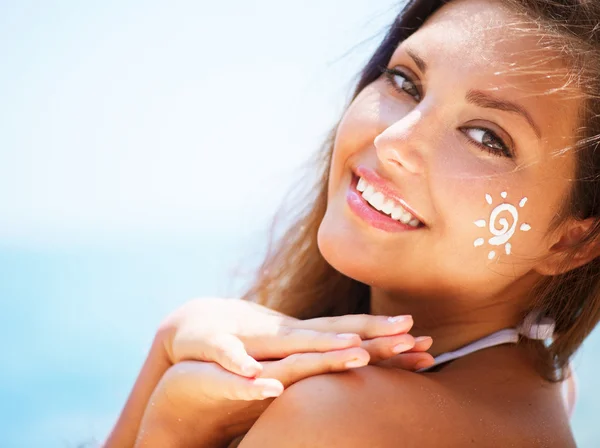 Mooi blij meisje toe te passen zon tan crème op haar gezicht — Stockfoto