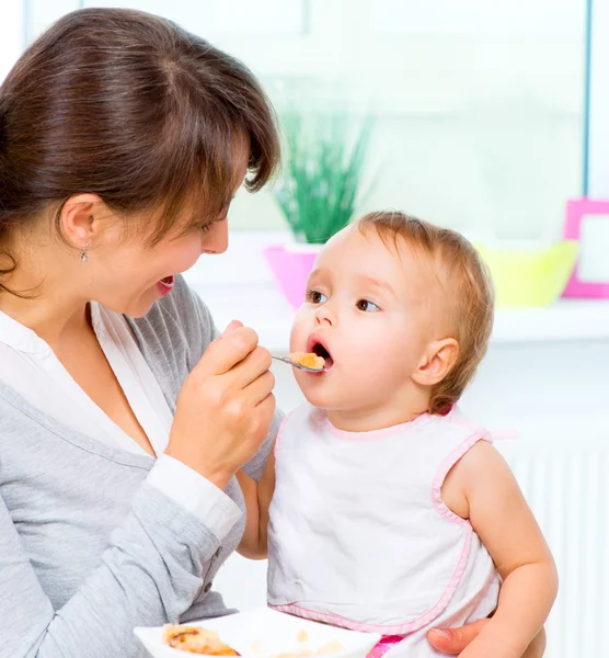 Mother Feeding Her Baby Girl with a Spoon Stock Photo