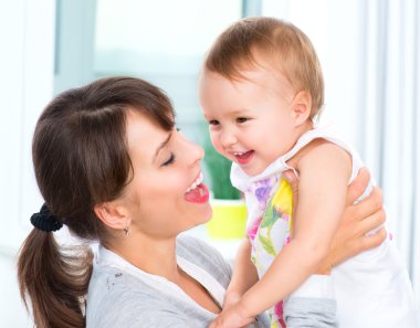 mutlu anne ve bebek öpüşme gülümseyerek ve evde sarılma