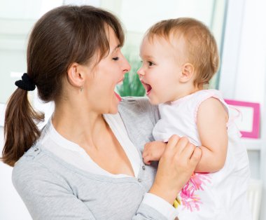 mutlu anne ve bebek öpüşme gülümseyerek ve evde sarılma