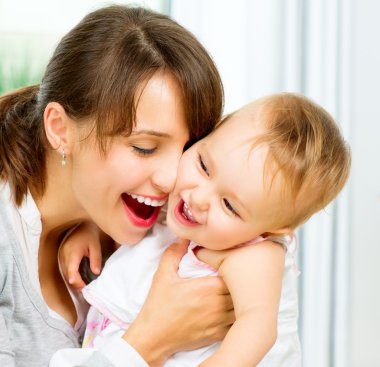 mutlu anne ve bebek öpüşme gülümseyerek ve evde sarılma