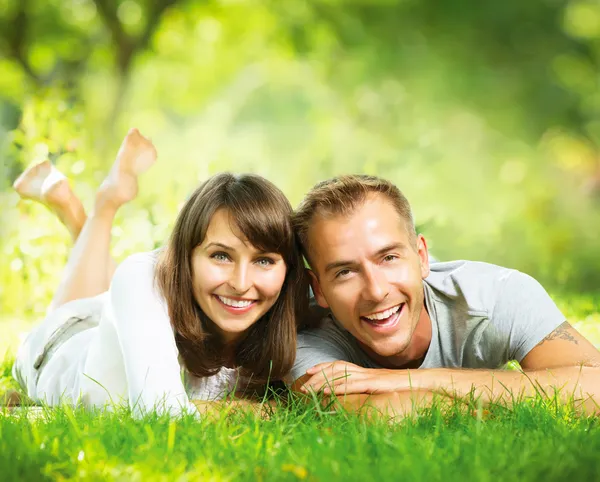 Gelukkige lachende paar samen ontspannen op groen gras buiten — Stockfoto