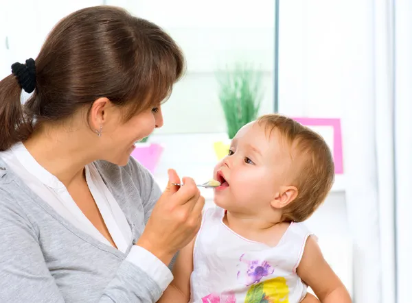 Moeder voeden haar baby meisje met een lepel — Stockfoto